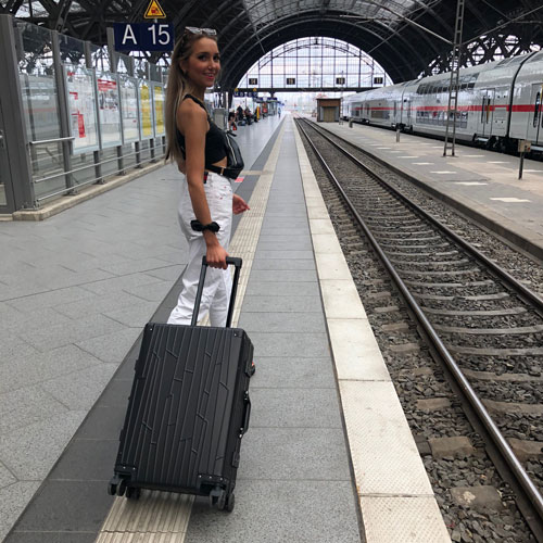 Frau mit schwarzem GUNDEL-Koffer auf Bahnsteig, bereit zum Einsteigen.