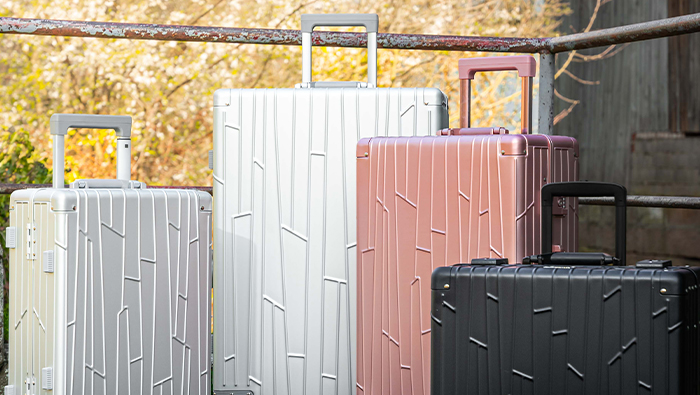 Vier GUNDEL Koffer in Silber, Space Grey, Roségold und Schwarz im Sonnenlicht.